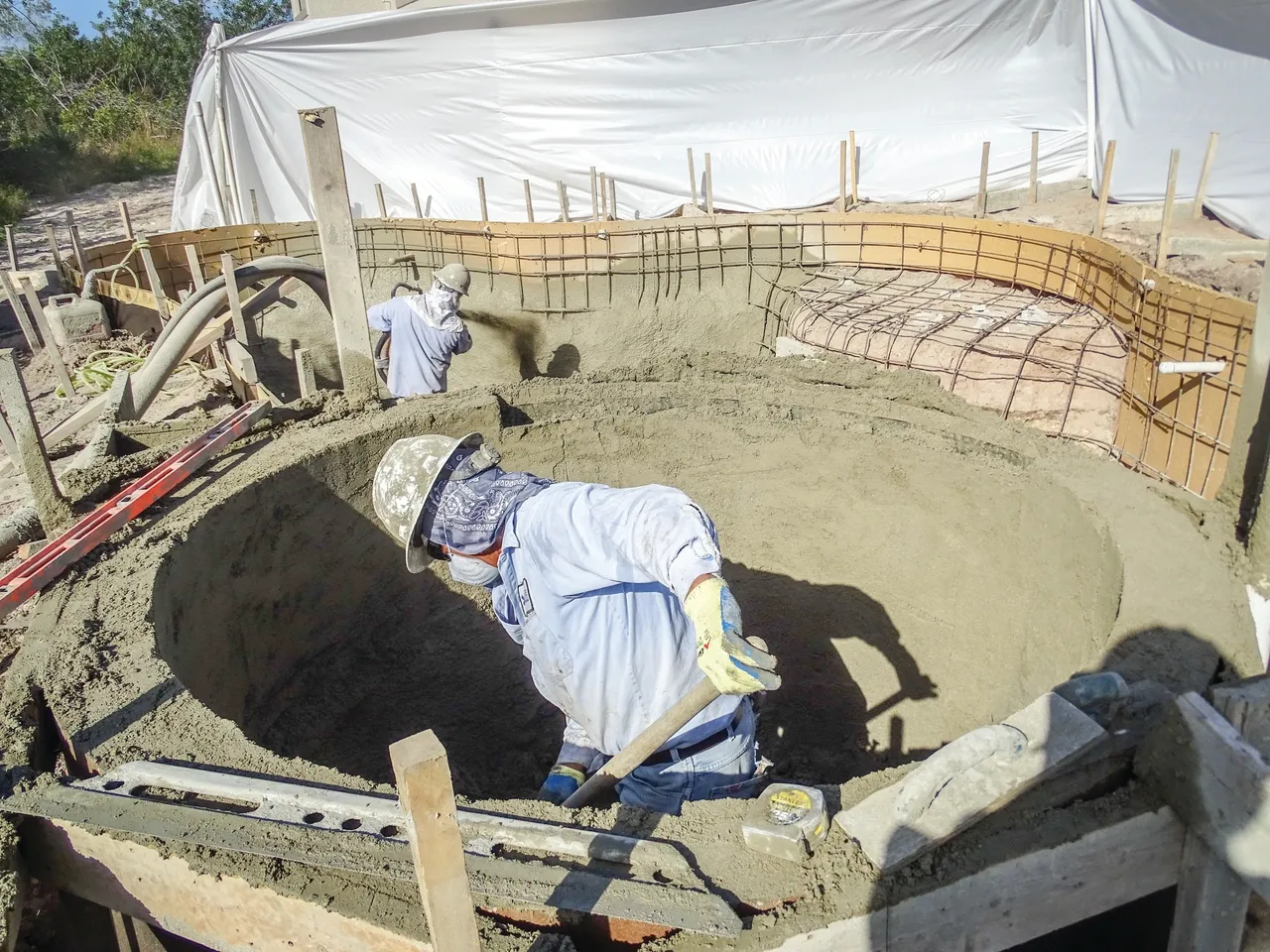 A man in white shirt and blue pants working on concrete.