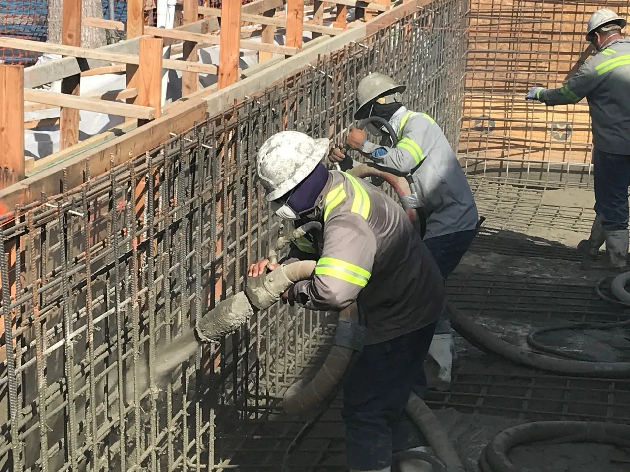 Two construction workers are working on a wall.
