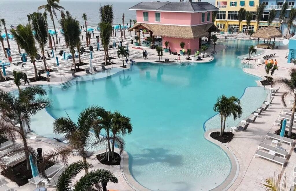 A pool with palm trees and a pink house