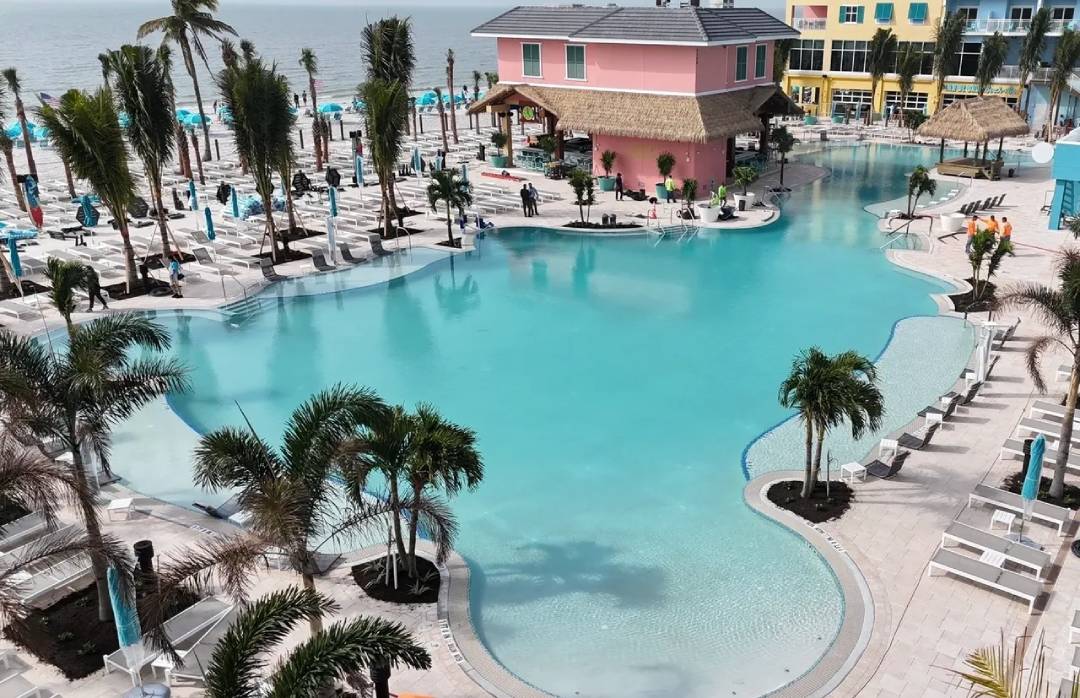 A pool with palm trees and a pink house