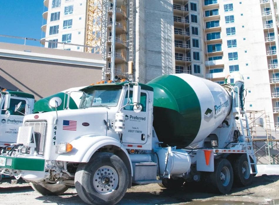A cement truck parked in front of some tall buildings.