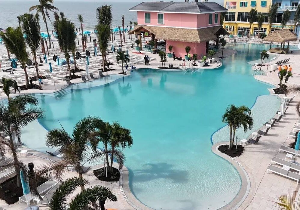 A pool with palm trees and a pink house